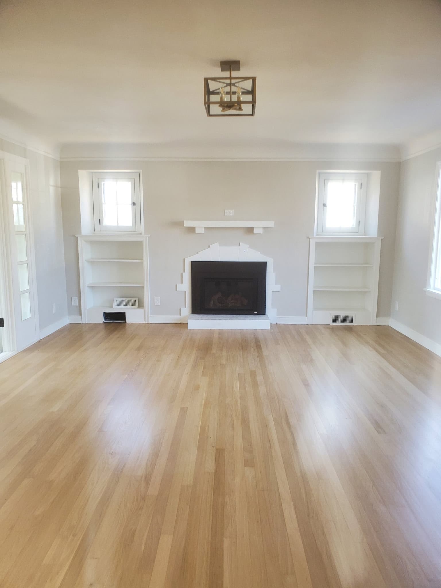 Refinished living room with a white fireplace surround, mantel, and flanking built-in shelving